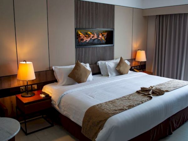 This image shows a well-decorated hotel room with a neatly made bed, bedside tables with lamps, and a modern wall design.