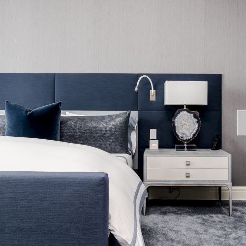 Modern bedroom with a blue and grey color scheme, featuring a bed, pillows,