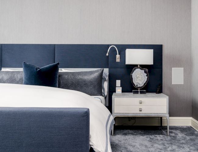 Modern bedroom with a blue and grey color scheme, featuring a bed, pillows,