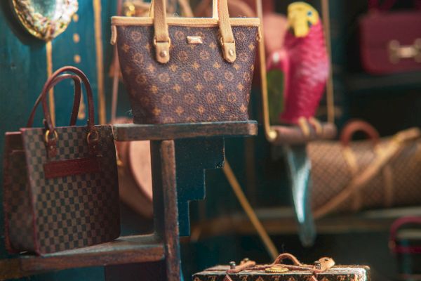 The image shows a display of luxury handbags on shelves with a mirror on the left side, set against an elegant backdrop.