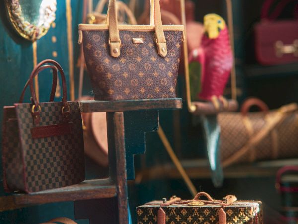 The image shows a display of luxury handbags on shelves with a mirror on the left side, set against an elegant backdrop.