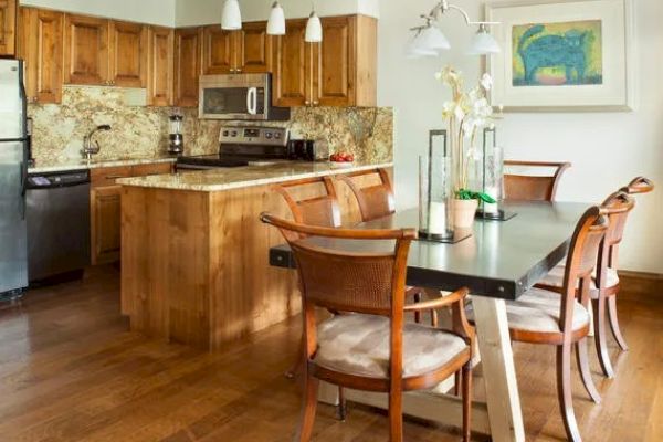 A modern kitchen and dining area with wooden cabinets, stainless steel appliances, a central island, and a dining table with chairs.