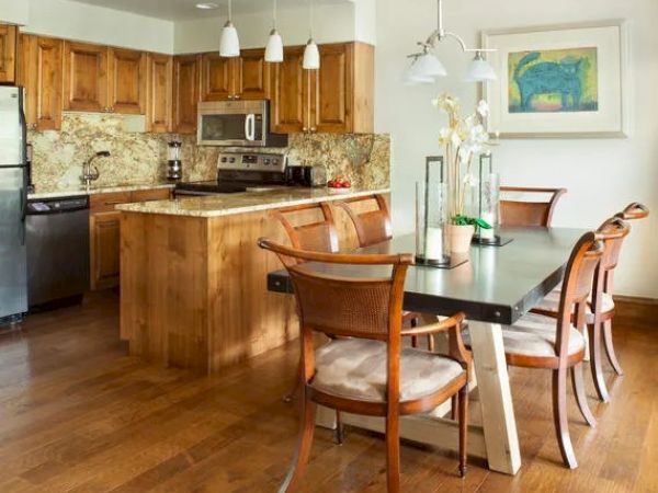 A modern kitchen and dining area with wooden cabinets, stainless steel appliances, a central island, and a dining table with chairs.