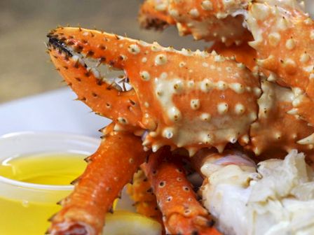 The image shows crab legs on a plate, with a small cup of melted butter, ready to be served as a dish.