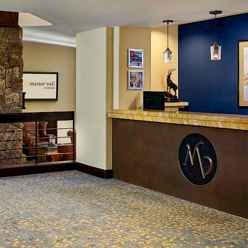 The image shows a hotel lobby with a reception desk, a stone fireplace, a staircase, framed art on the walls, and modern decor elements ending the sentence.