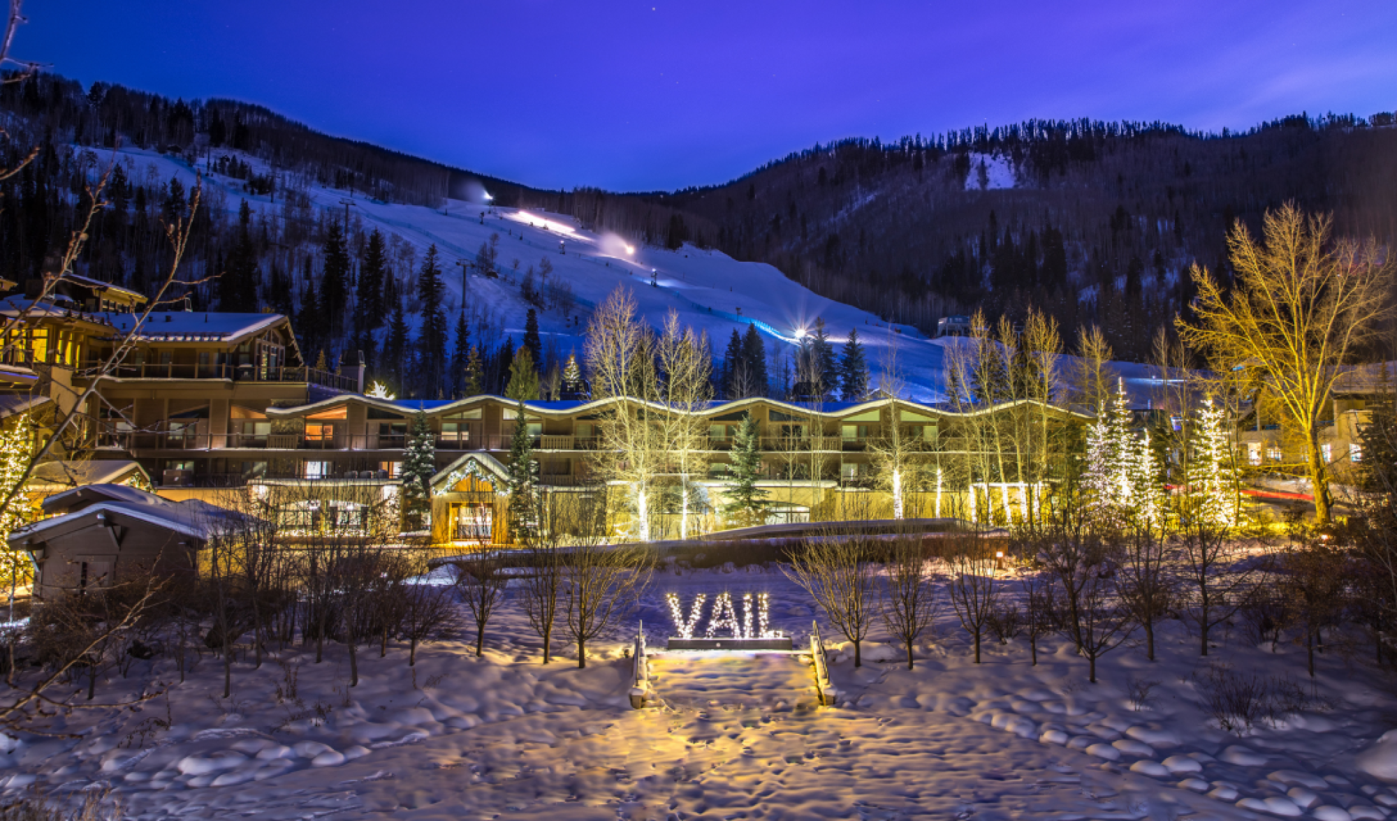 A snowy landscape with a well-lit building and sign reading 