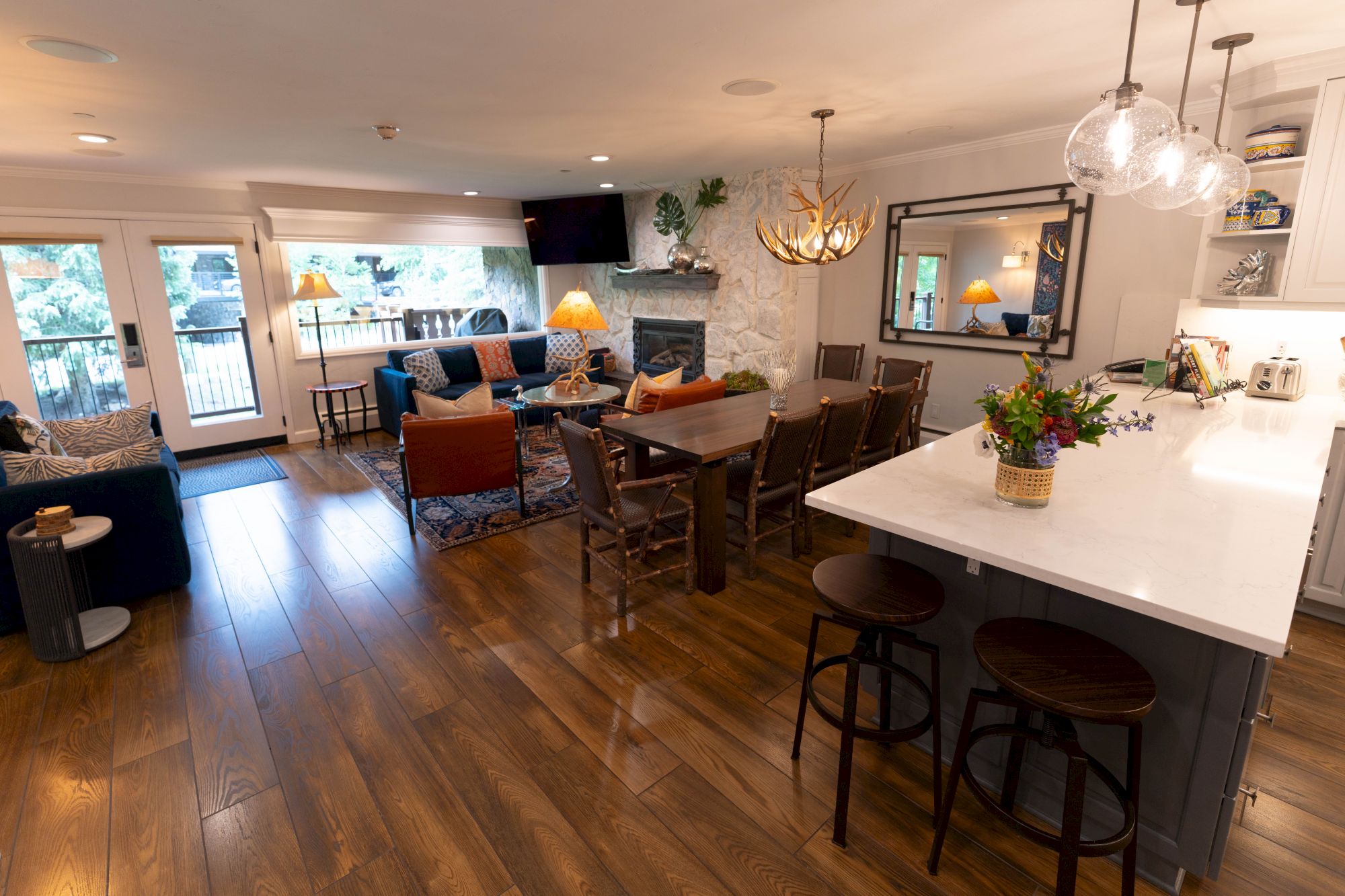 A cozy open-plan living area features a kitchen with a breakfast bar, dining table, and a comfortable seating area by the fireplace.