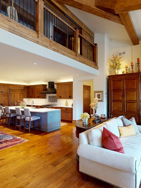A bright open-plan kitchen and dining area with wood beams, a stone fireplace, and elegant d&eacute;cor throughout.